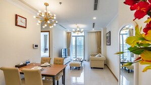 A modern hotel room with a dining area, a living room, and a balcony with a city view. - DongDong LUX APT - Vinhomes Central Park (Ho Chi Minh City)