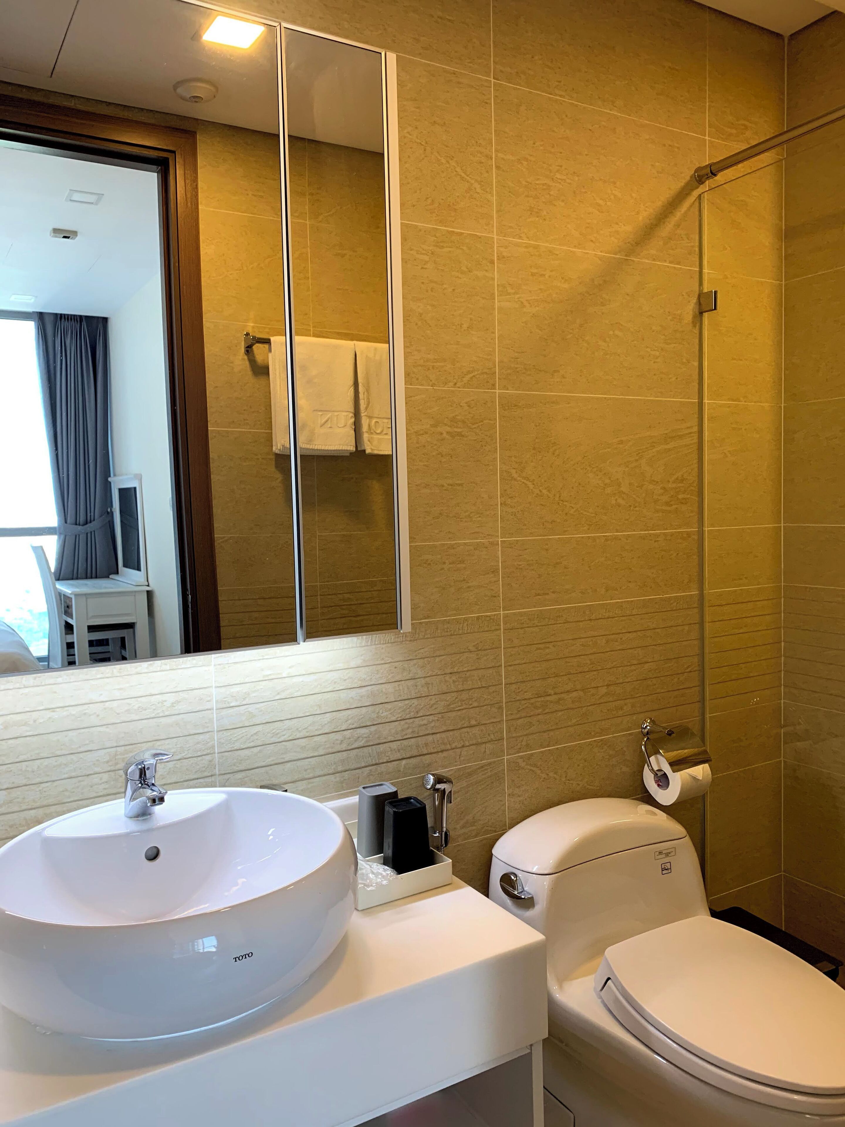 A bathroom with a white sink, toilet, and a glass shower enclosure.