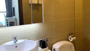A bathroom with a white sink, toilet, and a glass shower enclosure.