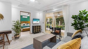 A modern living room with a sofa, coffee table, and a bed with a view to a balcony. - Stylish Ground floor Condo  walking to Town (Tamarindo)