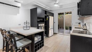 A modern kitchen with a dining area, built-in appliances, and a sliding glass door leading to a patio. - Stylish Ground floor Condo  walking to Town (Tamarindo)