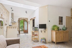 Ein Wohnzimmer mit Sofa, Fernseher, Holzschrank und Steinwand.