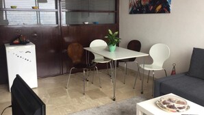 A small, modern room with a dining table, chairs, a sofa, and a TV. - Gauthier  (Casablanca)