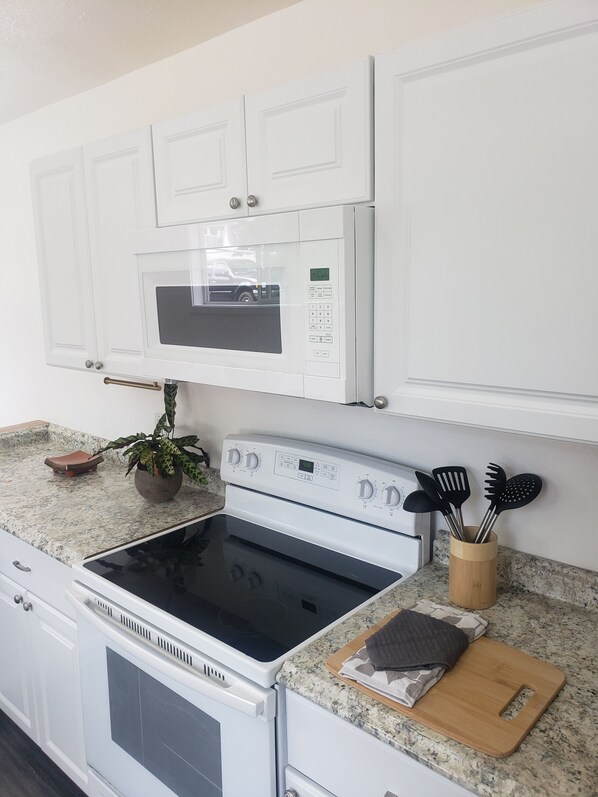 A kitchen with white cabinets, a microwave, an oven, and a stove.