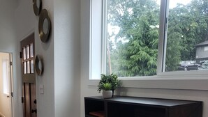 A room with a built-in shelf above a window, a brown chair, and a door with a mirror and decorative plates. - Downtown Stay at the Blue Tiny Twin (Roseburg)