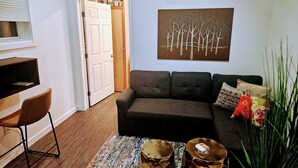 A living room with a sofa, coffee table, and a painting on the wall. - Downtown Stay at the Blue Tiny Twin (Roseburg)