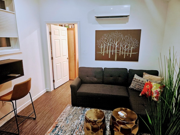 A living room with a sofa, coffee table, and a painting on the wall.
