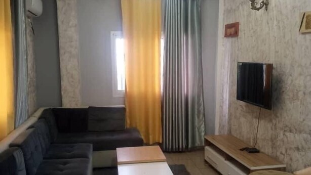 A living room with a sectional sofa, a coffee table, a TV stand, and a patterned rug. - LA DIVA (Douala)