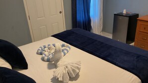 Ein Hotelzimmer mit Bett, Schreibtisch, Kommode und einem Fenster mit Vorhängen.