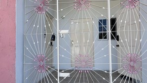 Ein moderner Hauseingang mit einem geometrisch gestalteten Metallgitter und einer Fußmatte.