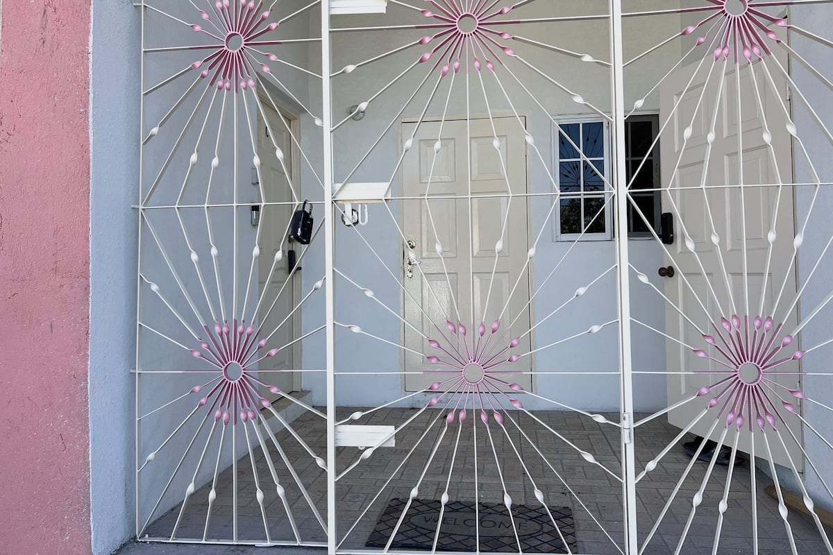 A modern building entrance with a geometric metal gate design and a welcome mat.