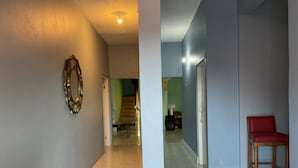 Un pasillo con un espejo, una escalera y una silla roja.