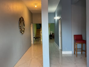 A hallway with a mirror, a staircase, and a red chair. - A taste of Jamaica Lavern place  (Ocho Rios)