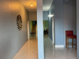 Un pasillo con un espejo, una escalera y una silla roja.