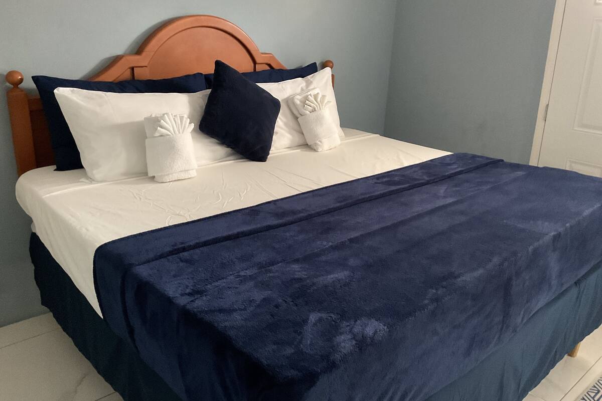 A bed with a wooden headboard, white bedding, and a navy blue blanket.