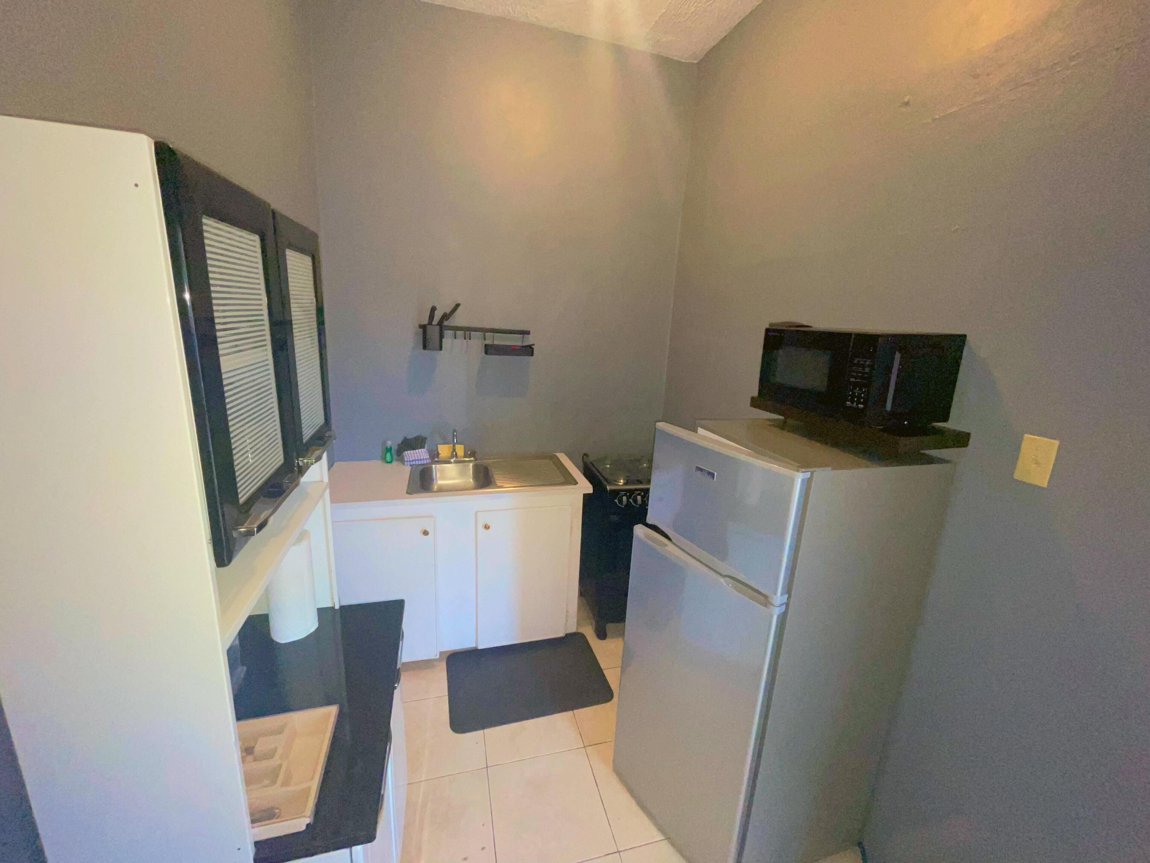 A compact kitchen with a refrigerator, microwave, sink, and a small countertop.