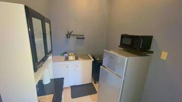 A compact kitchen with a refrigerator, microwave, sink, and a small countertop.