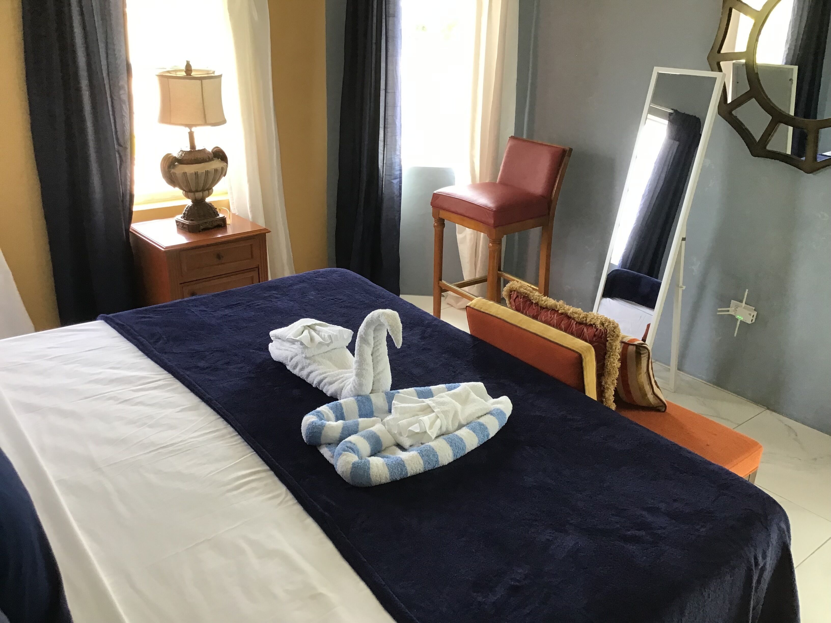 Une chambre d’hôtel avec un lit bien fait, une chaise, une lampe et un miroir.