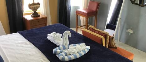 Une chambre d’hôtel avec un lit bien fait, une chaise, une lampe et un miroir.