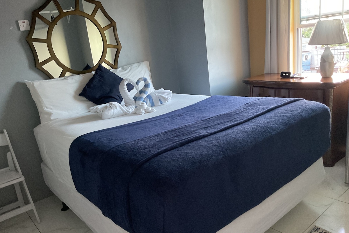 A neatly made bed with a blue blanket, white pillows, and a decorative headboard.