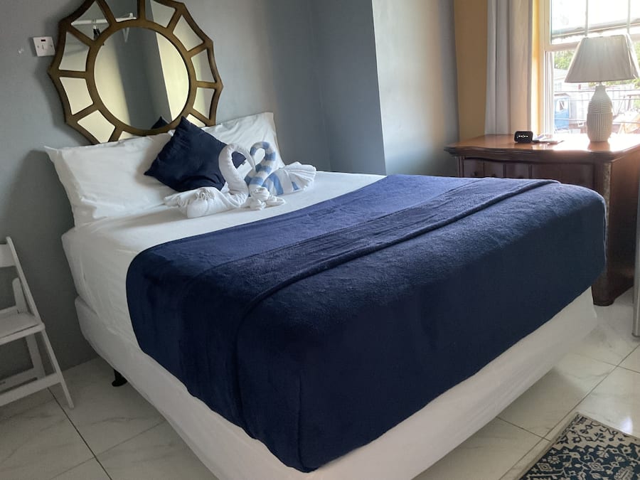 A neatly made bed with a blue blanket, white pillows, and a decorative headboard.