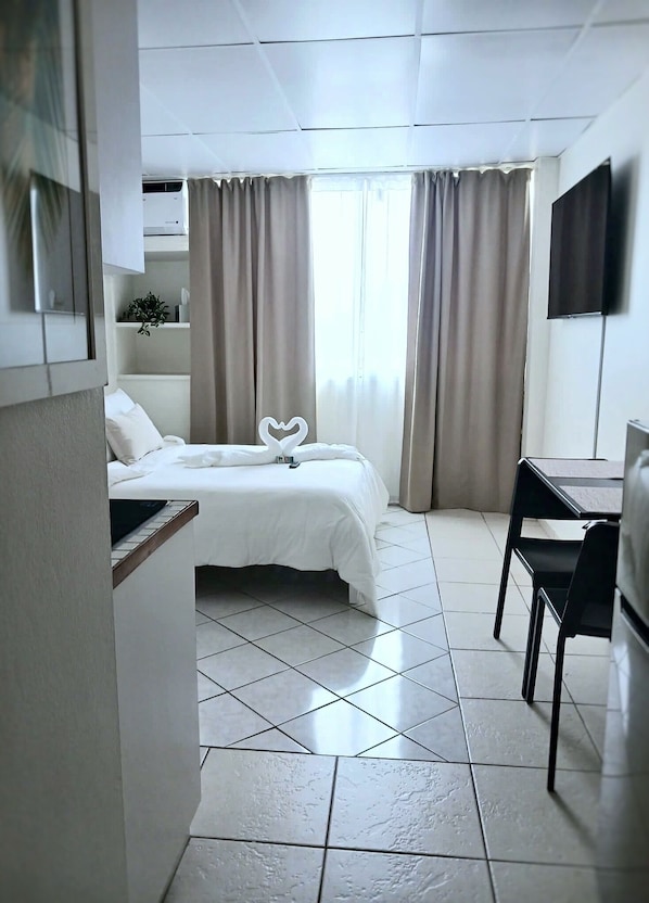 Une chambre d’hôtel avec un lit, un bureau et une chaise.