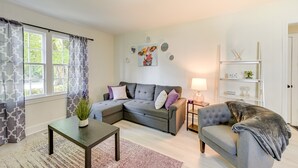 Una sala de estar con un sofá modular, una mesita, una silla, una lámpara y una estantería.