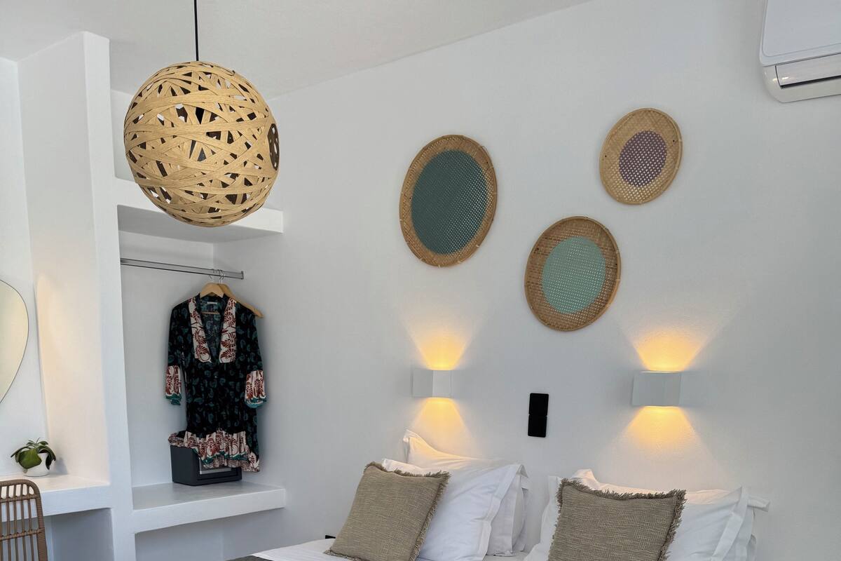 A modern bedroom with a large bed, a hanging light fixture, and wall-mounted decorative items.