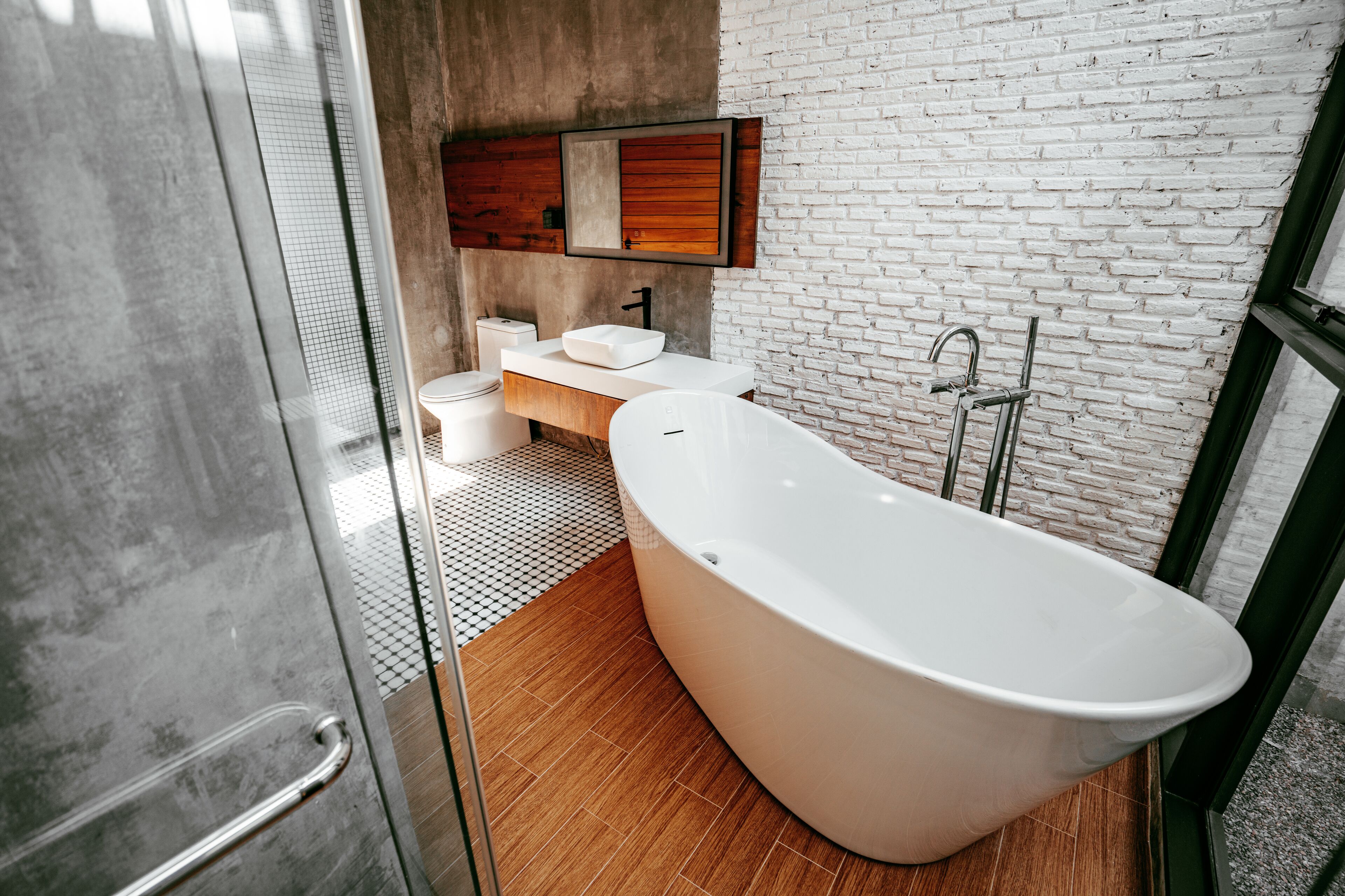 A modern bathroom with a freestanding bathtub, a wooden vanity, and a large mirror.