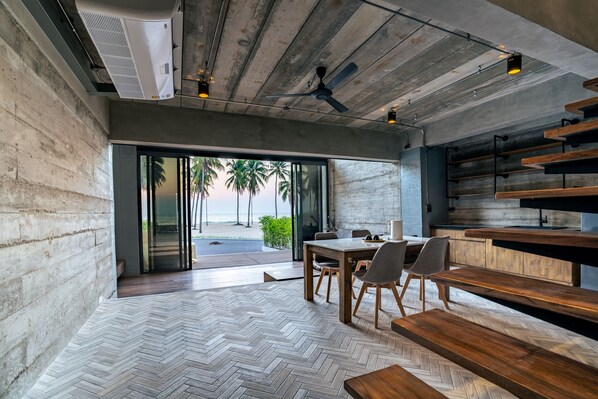 Un interior moderno con suelo de espiga, muebles de madera y vistas a palmeras a través de amplios ventanales.