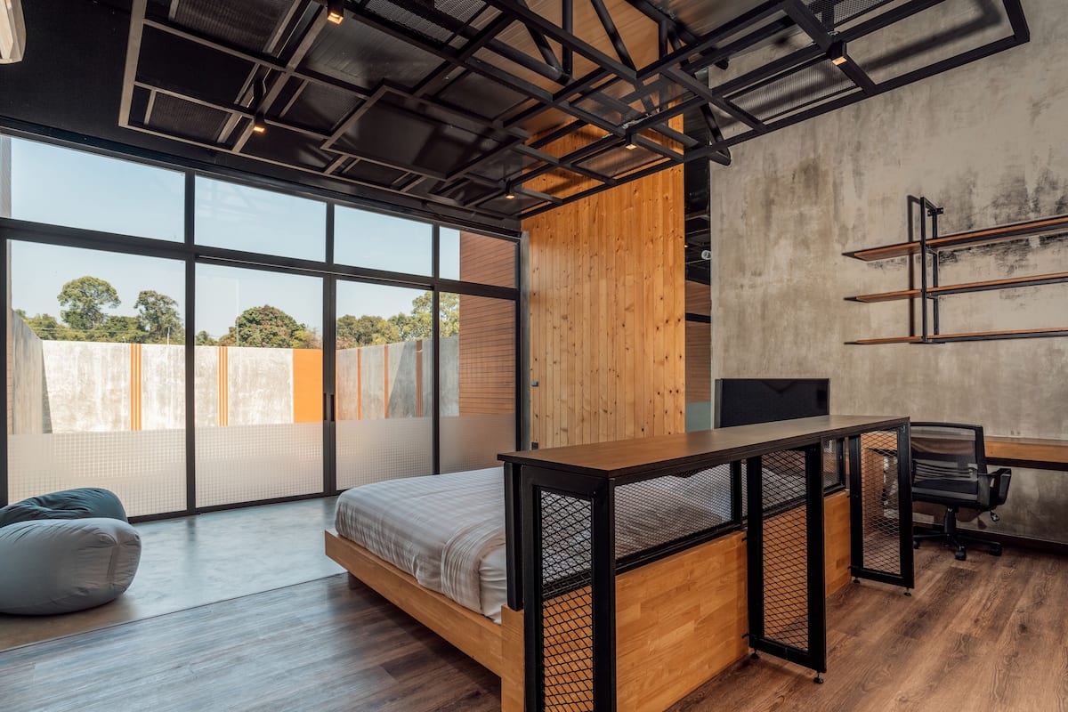 A modern room with a bed, desk, and large windows.