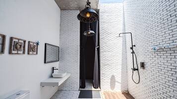 Un bagno moderno con una parete in mattoni bianchi, piastrelle esagonali, un lavandino bianco, un water e una doccia con tenda nera.
