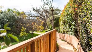 A wooden pathway bordered by lush greenery and a stone wall. - Coastal Guest House in Nature (Carpinteria)