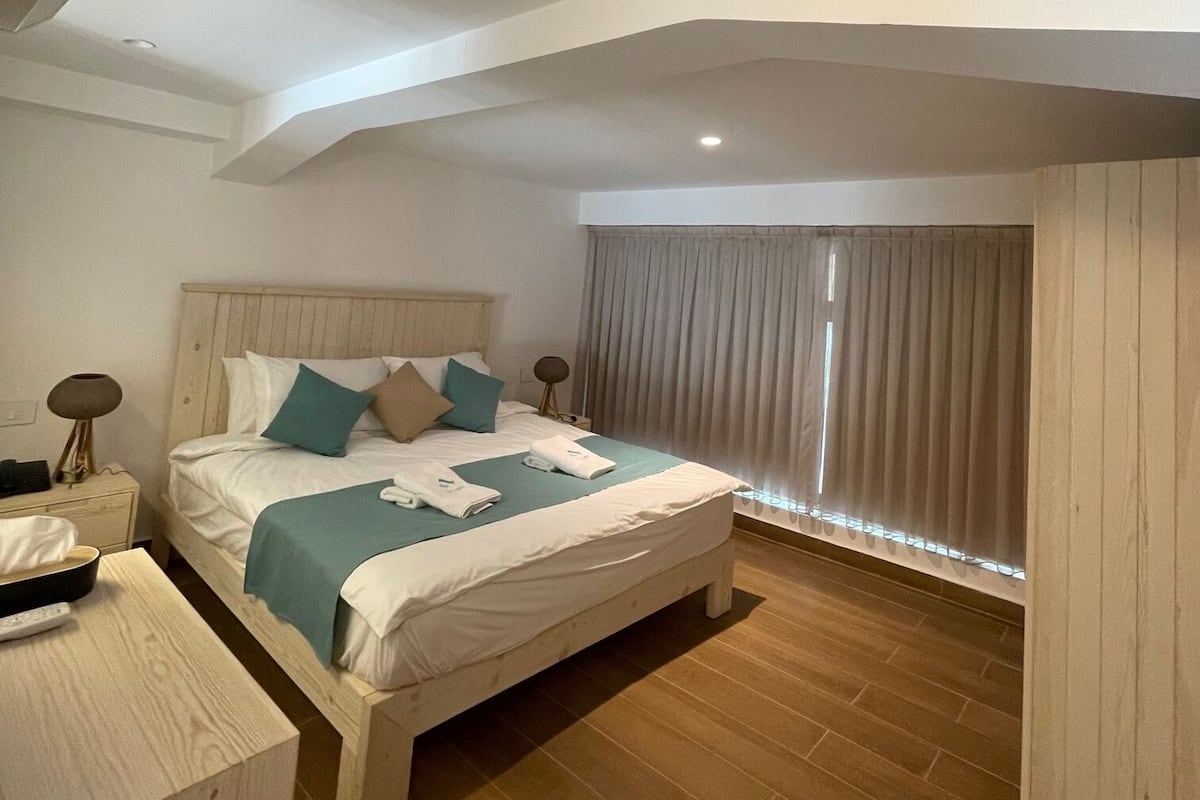 Un dormitorio moderno con una cama grande, una mesita de noche, una lámpara y una luz en el techo.