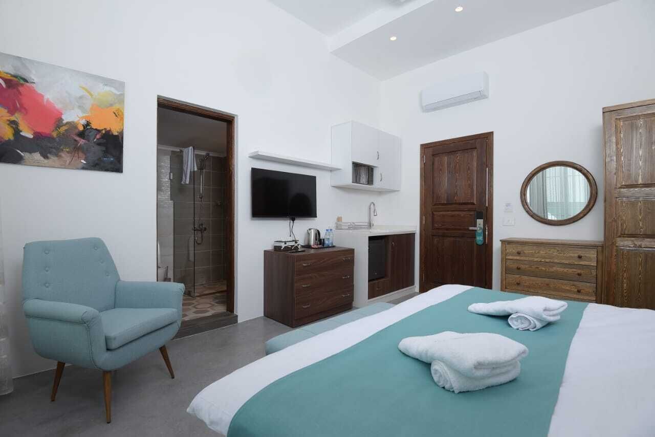 Une chambre d’hôtel comprenant un lit, une chaise, une télévision, une armoire et une salle de bain.