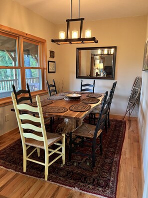 Una sala da pranzo con un tavolo in legno, sedie bianche e nere, un lampadario e un grande specchio.