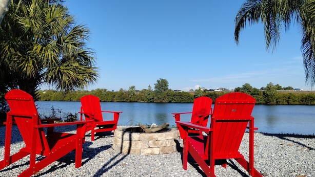 Un espace aménagé au bord du lac, avec des chaises Adirondack rouges et un foyer en pierre.
