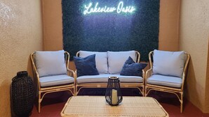 Un coin salon avec des meubles en osier et un panneau lumineux au néon.