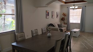 Un coin repas comprenant une table, des chaises, un vase avec des fleurs, un canapé et une lampe.