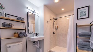 A modern bathroom with a toilet, sink, shower, and towel racks. - Modern Seattle Townhome Near Downtown & Parks (Seattle)