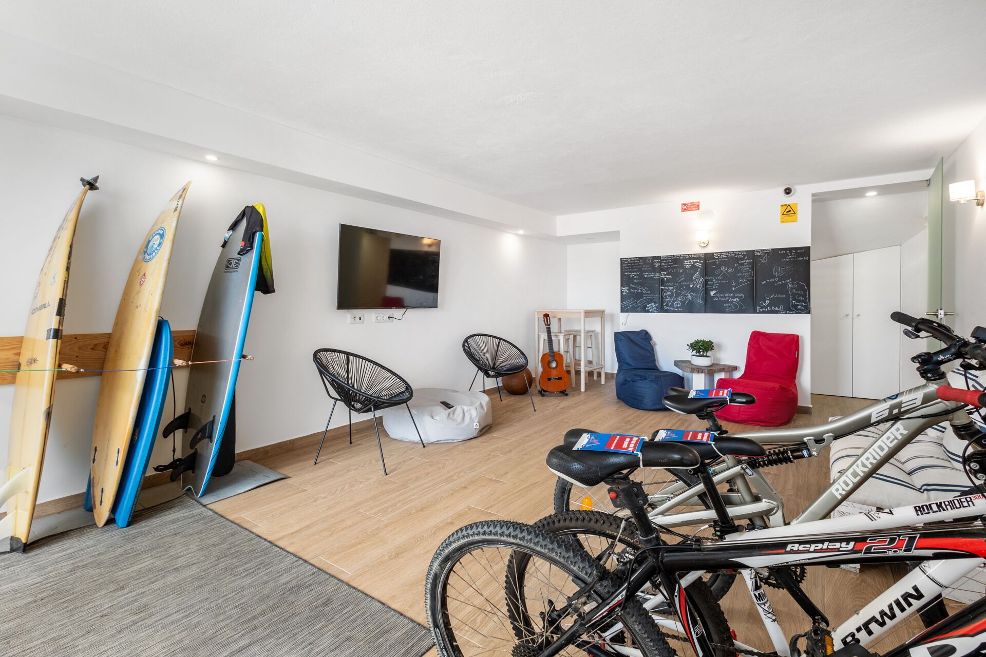 Ein modernes Wohnzimmer mit Fernseher, Surfbrettern, einer Gitarre und einem Fahrrad.