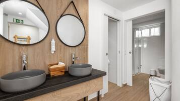 A modern bathroom with two sinks, wooden paneling, and a mirror.