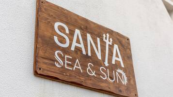 Uma placa de madeira com o texto 'SANTA SEA & SUN' fixada em uma parede.