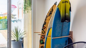 Deux planches de surf appuyées contre un mur, une plante en pot et une chaise.
