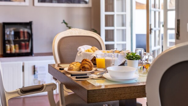 Une table de petit-déjeuner avec des croissants, du jus d’orange et un bol de céréales.