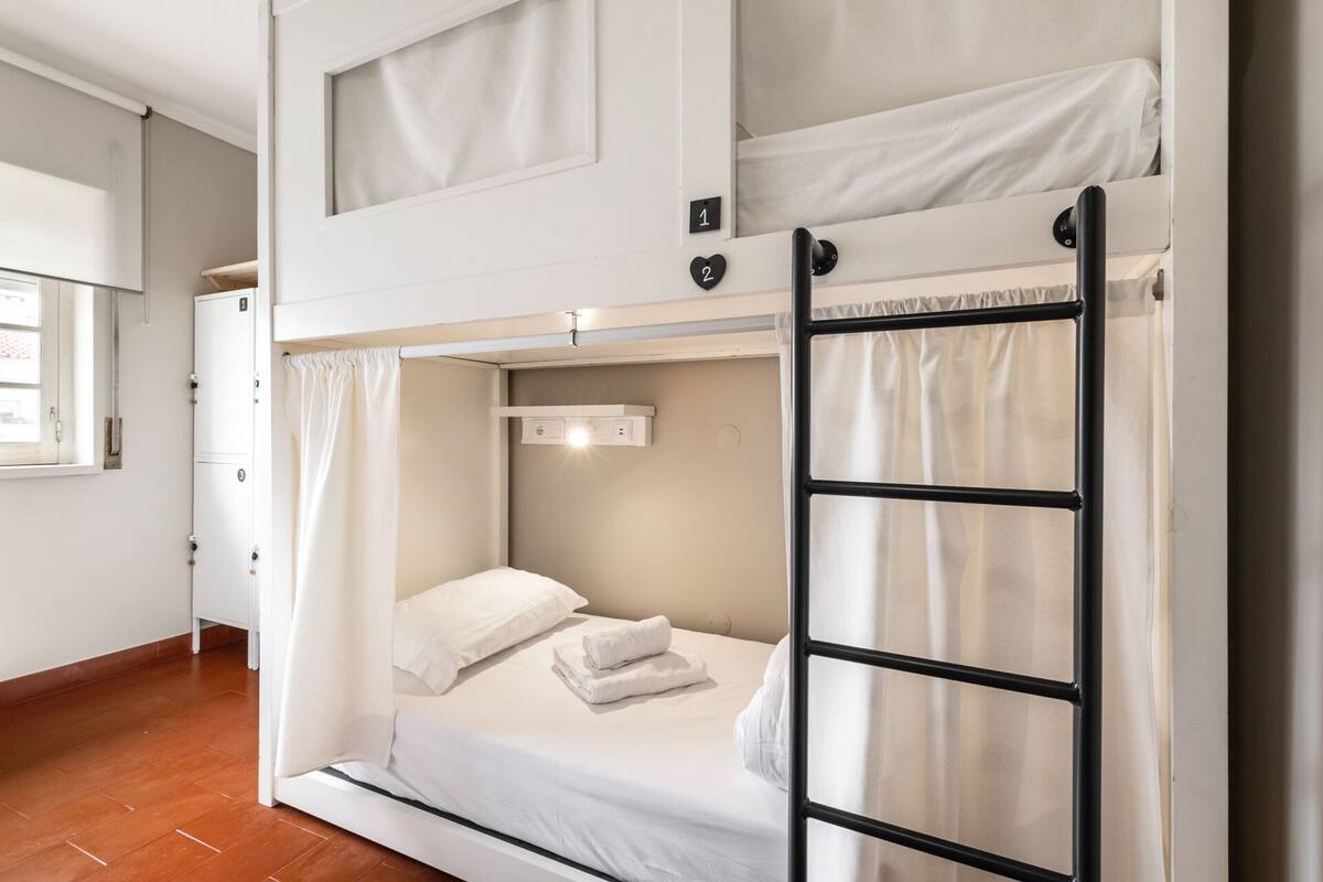 A bunk bed room with a ladder, a window, and a door.