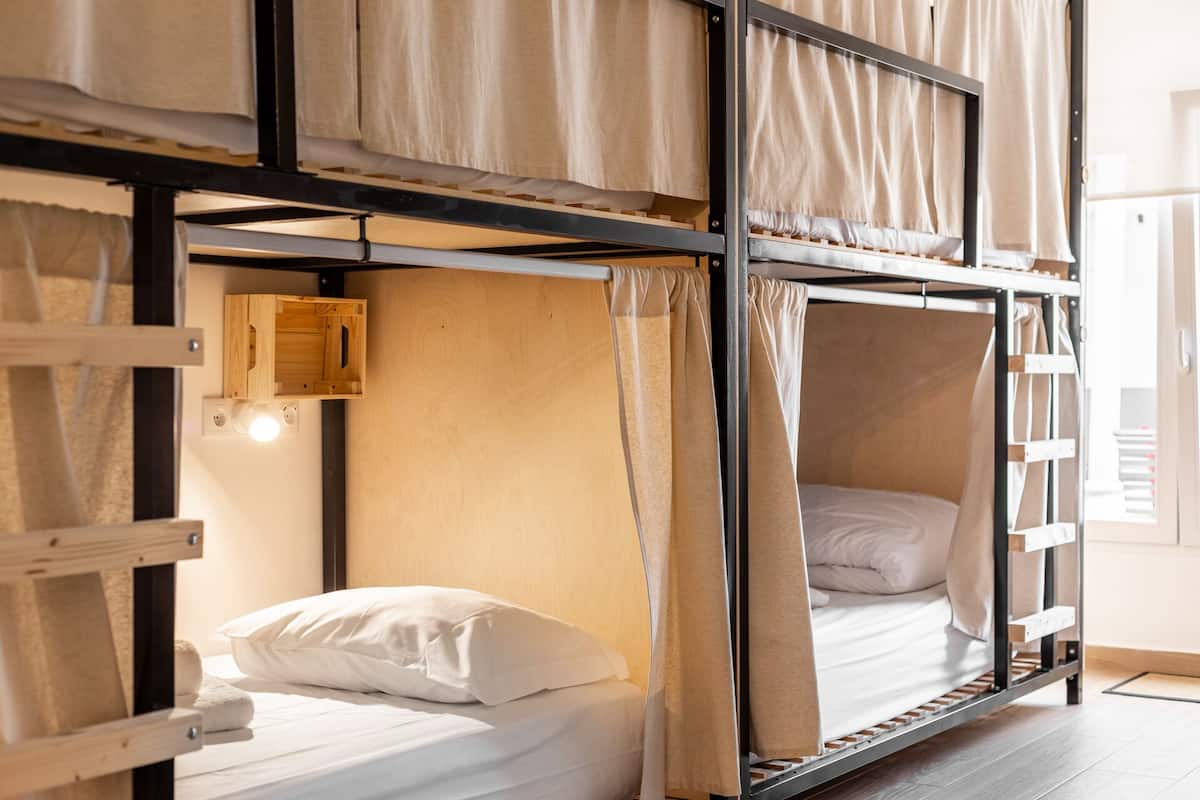 A bunk bed room with a wooden ladder, a small wooden cabinet, and a light fixture.