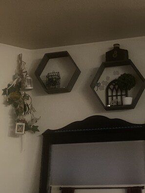Guest room with a large window, wall-mounted shelf, and three hexagonal mirrors.