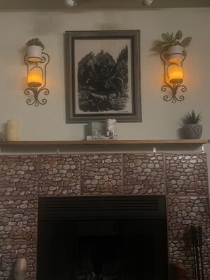 A fireplace with a stone facade, a framed artwork above it, and two wall-mounted lamps on either side. - SC WA work Rental (Renton)