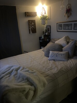 Cozy retreat with a plush bed, bedside table, and soothing decor.